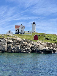 Lighthouse by sea against buildings