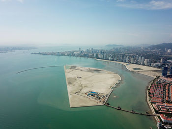 High angle view of city by sea against sky