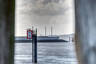 Information sign by sea against sky