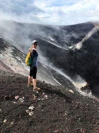 Side view of woman standing on mountain against sky