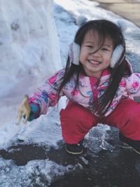 Full length portrait of cute girl playing with snow during winter
