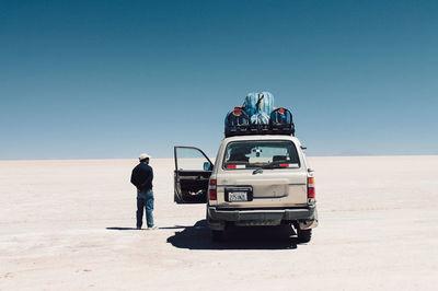 People standing on desert against clear sky