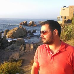 Young man looking at sea shore against sky