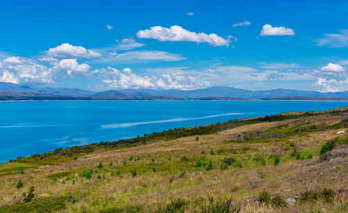 Scenic view of sea and mountains against blue sky