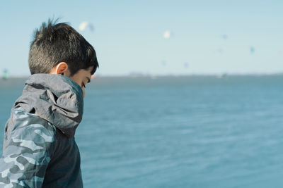 Side view of boy looking at sea against sky