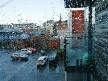 Cars on road seen through wet window during rainy season