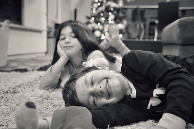 Siblings lying on carpet at home