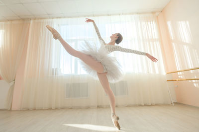 Full length of young woman jumping against wall