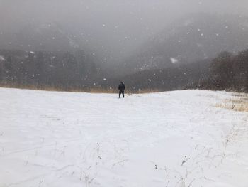 Man walking through snow storm in snow covered field