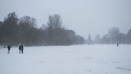 People on snow covered field against sky