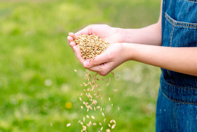 Midsection of woman holding plant on field