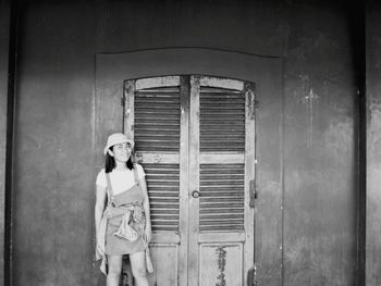 Portrait of smiling woman standing by closed door