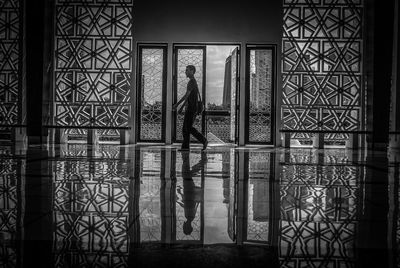 Reflection of silhouette man standing on glass window