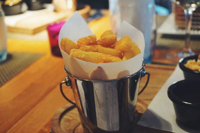 Close-up of french fries served in bucket on table