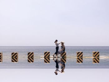 People enjoying on beach against clear sky