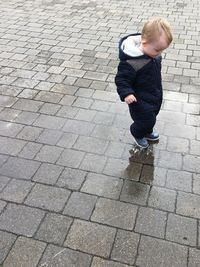 High angle view of boy standing on footpath during rainy season