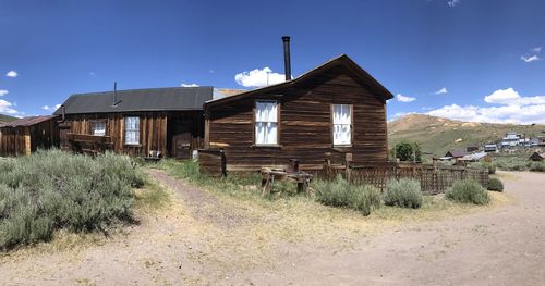 Old house on field by building against sky