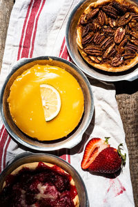 Baked artisan made lemon custard tart, pecan tart, and strawberry tart viewed from above 