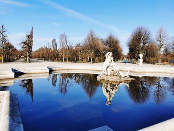 Statue by lake against blue sky