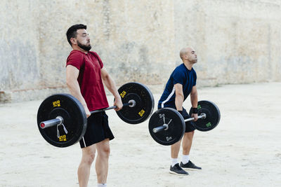 Two weightlifters lifting weights in an urban environment.