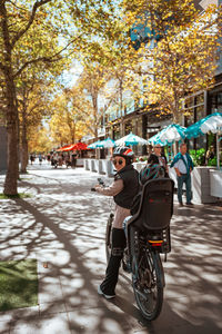 Rear view of man riding motor scooter on street