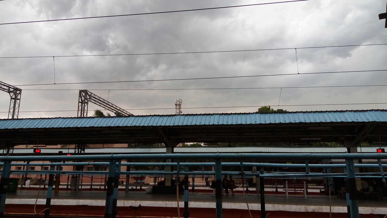 sky, architecture, built structure, cloud - sky, cloudy, transportation, railing, building exterior, connection, railroad station platform, railroad station, cloud, rail transportation, cable, railroad track, public transportation, low angle view, power line, day, bridge - man made structure