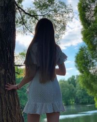 Woman standing by tree against plants