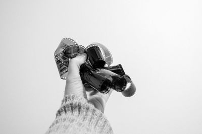 Cropped hand of woman holding camera film against white background