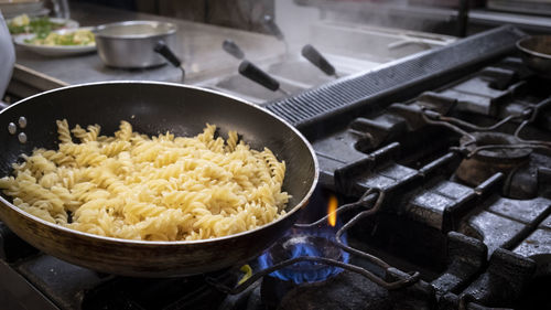 Preparation of fusilli dish with cooking pan on the stove, italy