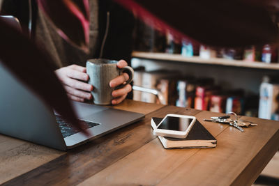 Midsection of woman using laptop on table at cafe