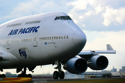 Airplane flying over airport runway against sky