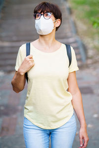 Woman wearing mask looking away standing outdoors