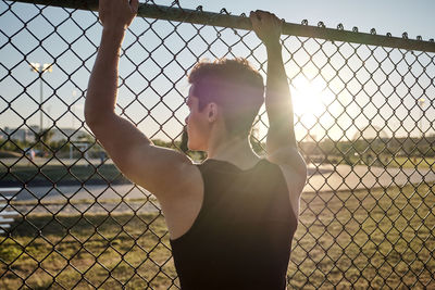 Woman standing by chainlink fence