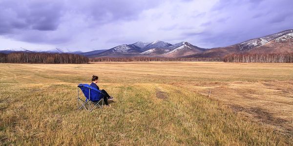 Rear view of woman on field against sky. minimalism. alone woman. kamchatka. 