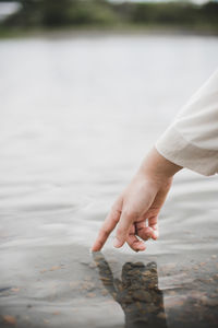 Cropped hand touching water in lake
