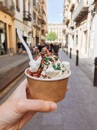 Midsection of person holding ice cream in city