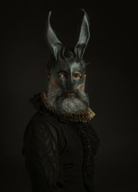 Portrait of a man with rabbit mask against black background