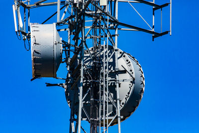 Low angle view of communications tower against clear blue sky