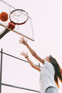 A young girl throws a ball into the basket and plays basketball. basketball, sports, game