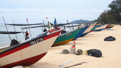 Boats moored on beach against sky