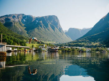 Full length of shirtless man jumping into lake against mountains