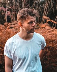 Young man looking away in forest