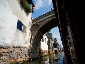 Arch bridge over canal amidst buildings against sky