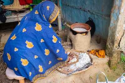 Women making rice floor bread in traditional soil vessels at wood fire from different angle