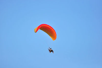 Low angle view of man paragliding against blue sky