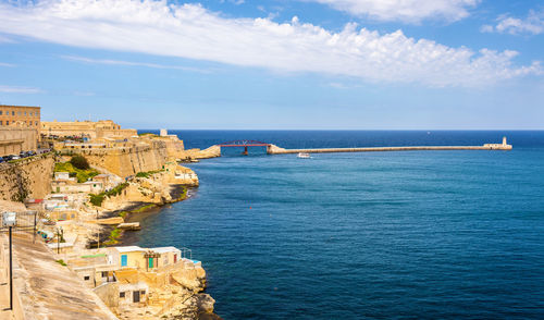 Scenic view of sea by buildings against sky