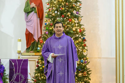 Portrait of priest praying while standing in church