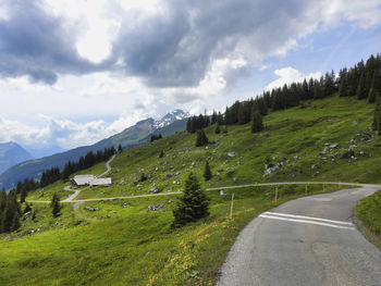 Scenic view of road by mountains against sky