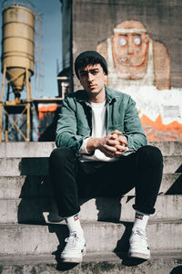 Full length of young man sitting on wall