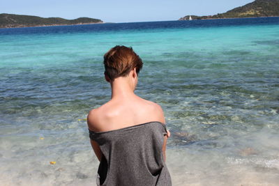 Rear view of young woman standing at beach